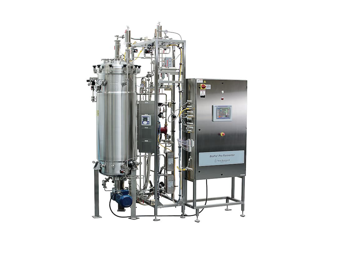 A stainless-steel bioreactor skid with vessel, piping and control cabinet.